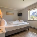 Schlafzimmer mit Bett, Fernseher und Fensterblick.