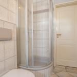 Badezimmer mit Dusche, Toilette und Tür.