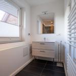 Badezimmer mit Waschbecken, Spiegel und Fenster.