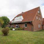 Rotes Ziegelhaus mit Balkon und Garten. Solaranlage auf Dach.