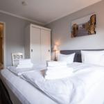 Schlafzimmer mit Bett, Kleiderkabinett und Wandbild. Blick in angrenzende Räume.