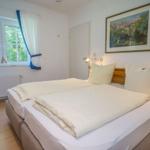 Schlafzimmer mit Doppelbett, Fenster und Wandbild.
