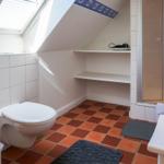 Badezimmer mit Dusche, Toilette und Waschbecken unter Dachschräge.
