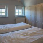 Schlafzimmer mit Doppelbett, zwei Fenstern und Kleiderschrank.