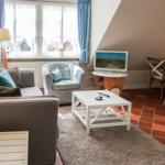 Wohnzimmer mit Sofa, Sessel, Fernseher und Esstisch.