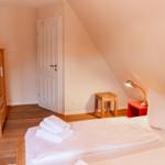 Bedroom with bed, wardrobe, and nightstand. Attic slope and wooden floor.