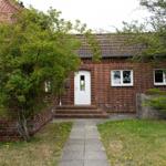 Red brick house with white door and paved walkway.