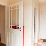 Entrance area with white doors and tiled floor. Staircase left, main door right.