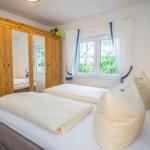 Bedroom with double bed, wooden wardrobe, and window with view of greenery.