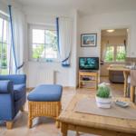 Living room with blue armchair, wooden table, and garden view.