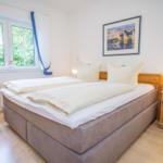 Bedroom with double bed, wooden cabinet, and window with view of greenery.