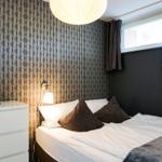 Schlafzimmer mit Bett, Nachttisch und Wandbeleuchtung.