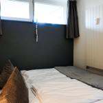 Schlafzimmer mit Bett, Fenster und Heizkörper an der Wand.