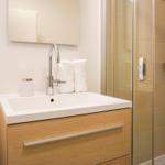 Bad mit Waschbecken, Spiegel und Dusche mit Glaswand
