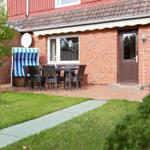 Red brick house with terrace, table, chairs, and beach chair.