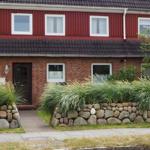 Red wooden house with stone wall and greenery
