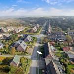 Aerial view of residential area with houses and greenery near coastline.