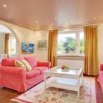 Living room with pink sofas, glass table, and garden view.