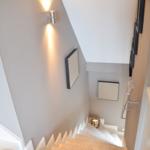Helle Treppe mit moderner Beleuchtung und Wanddekoration.