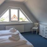 Schlafzimmer mit Dachschrägen, Fenster und Bett mit Handtüchern.