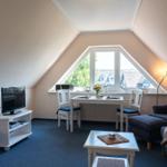 Zimmer mit Dachfenster, Tisch, Stühlen, Fernseher und Sitzgelegenheiten.