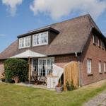 Red brick house with terrace and garden. White windows and sliding doors.