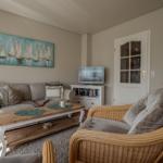 Living room with sofa, armchair, and TV. Wall art with sailboats.