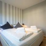 Schlafzimmer mit Bett, Kissen und Handtüchern. Wand mit Streifenmuster.