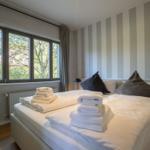Schlafzimmer mit Bett, Fenster und gestreifter Wand