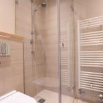 Badezimmer mit Dusche, Heizkörper und Toilette.