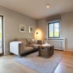 Wohnzimmer mit Sofa, Korbtablett und TV. Durchgangstür zum Balkon.