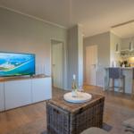 Wohnbereich mit TV, Esstisch und Küchenbereich.
