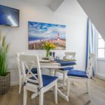 Dining room with white table, blue seat cushions, and lighthouse wall art.