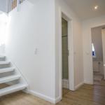 Bright entryway with staircase and view into bathroom and bedroom.