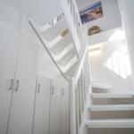 White staircase with closet and wall art in hallway