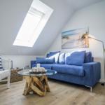 Living room with blue sofa, white chair, and skylight.