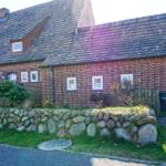Red brick building with slate roof and stone wall in the front garden.