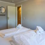 Room with bed, towels, chair, and mirror on the wall.