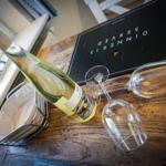 Wine bottle and two glasses on wooden table with dinner menu.