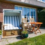 Terrace with beach chair, table and chairs beside house wall