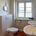 Bathroom with toilet, two sinks, and window