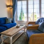 A living room with a blue sofa, two chairs, and large windows.