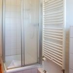 Shower with glass door, heater, and white tiles.