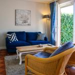 A living room with a blue sofa, two rattan chairs, and a wooden table.