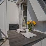 Terrasse mit Tisch, Stühlen und Blumenarrangement.