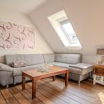 Ein Wohnzimmer mit grauem Sofa, Holztisch und Dachfenster.