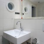 Badezimmer mit Waschbecken, Spiegel und runden Fenster