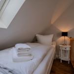 Schlafzimmer mit Dachschräge, Bett, Nachttisch und Fenster