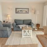Wohnzimmer mit grauem Sofa, Holzfußboden und Esstisch