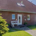 Haus mit rotem Ziegeldach, weiße Tür und Bank vor dem Eingang.